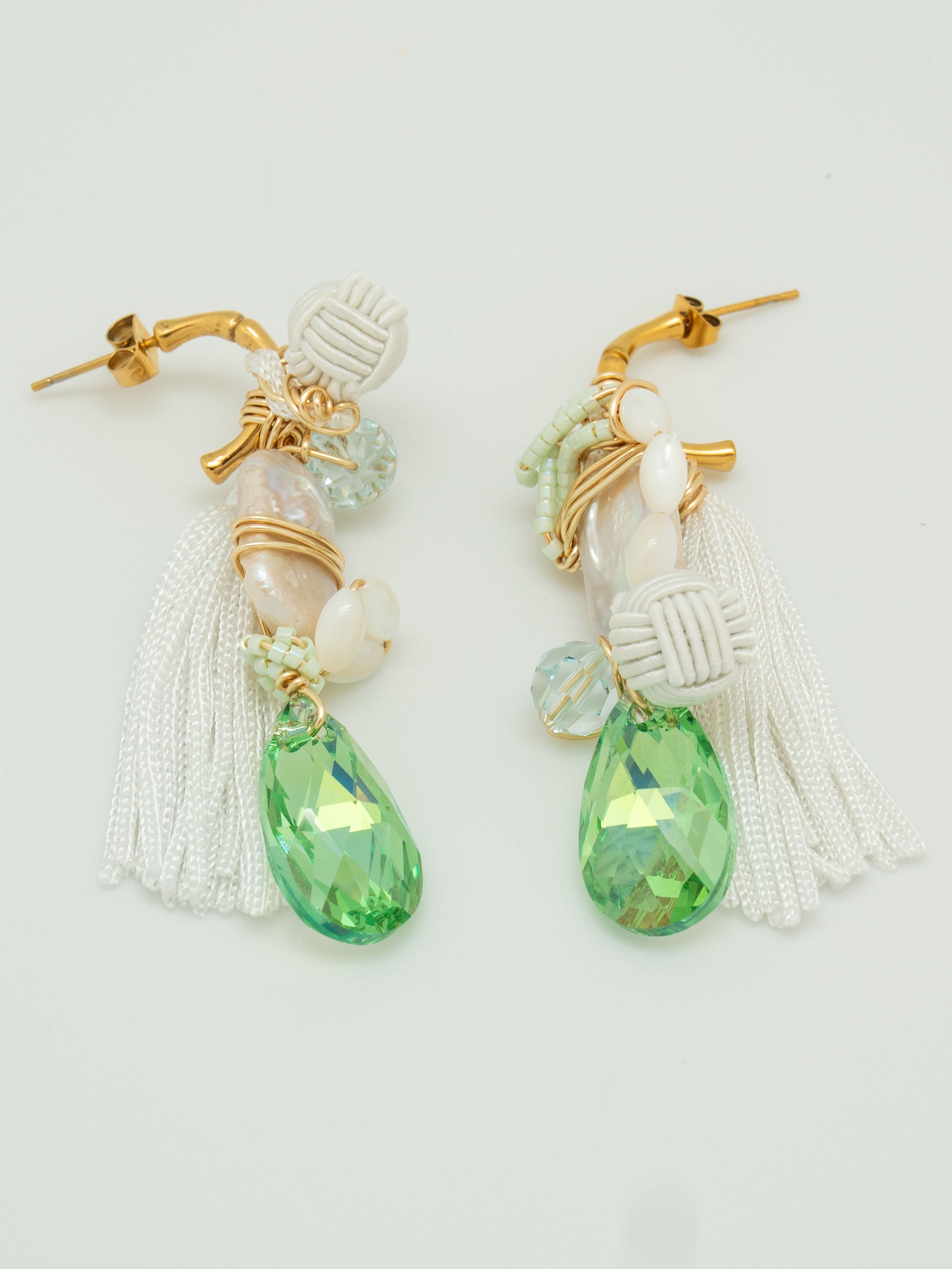Pair of earrings with green teardrop-shaped swarovski crystals, freshwater pearls, white tassel and fabric elements