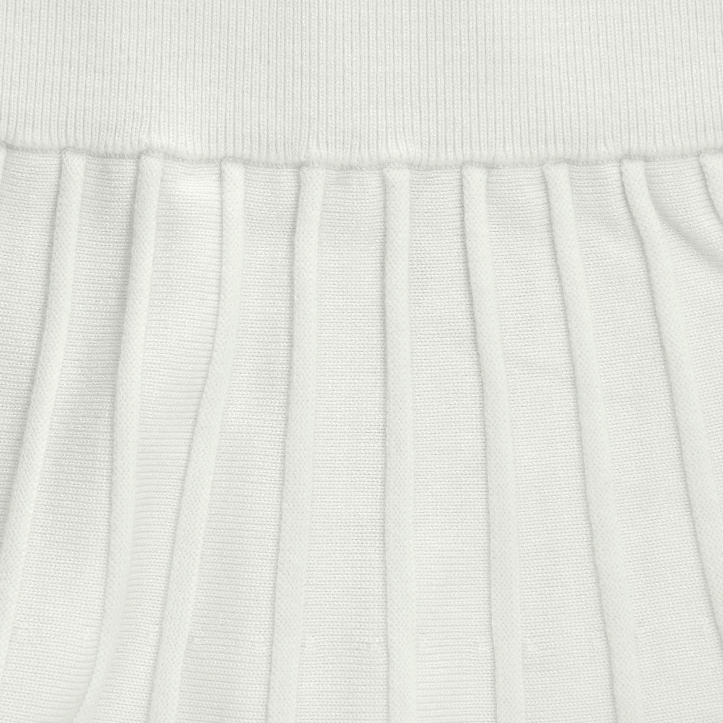 Close-up of a white textured knit fabric with pleated details
