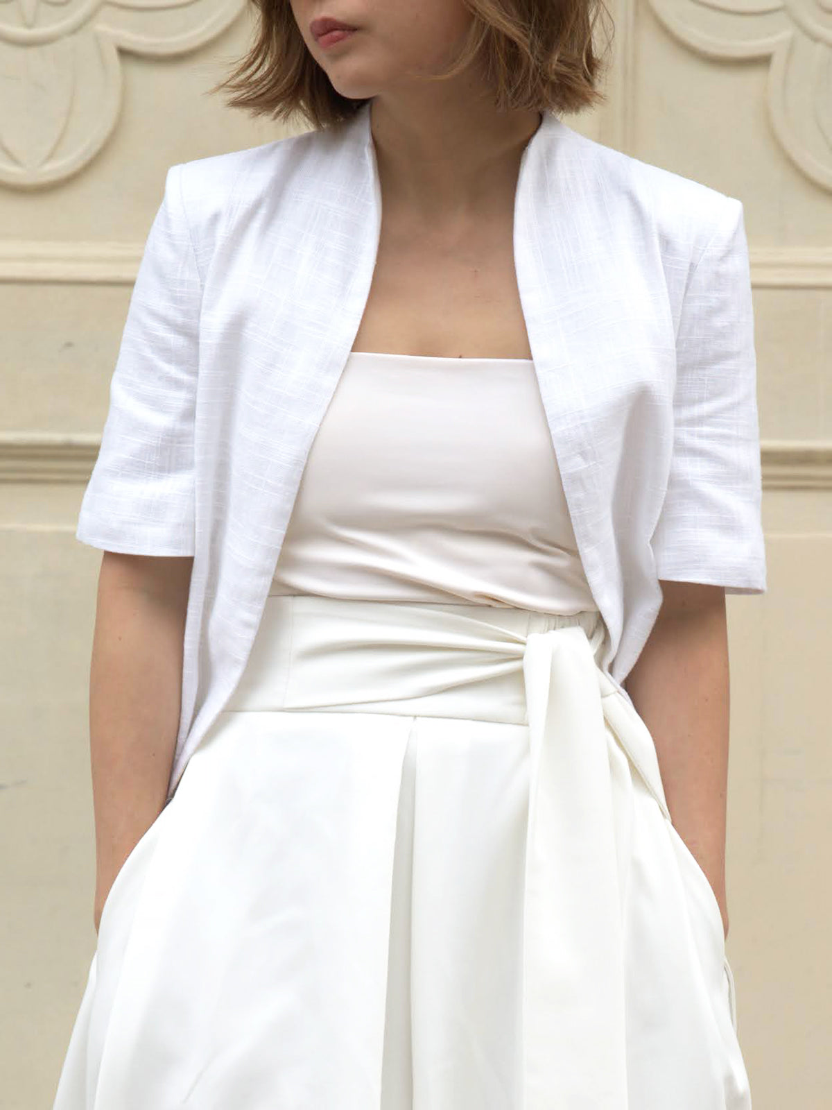 Woman wearing a white outerwear jacket with tailcoat and white skirt by Singapore fashion brand Hadasity.