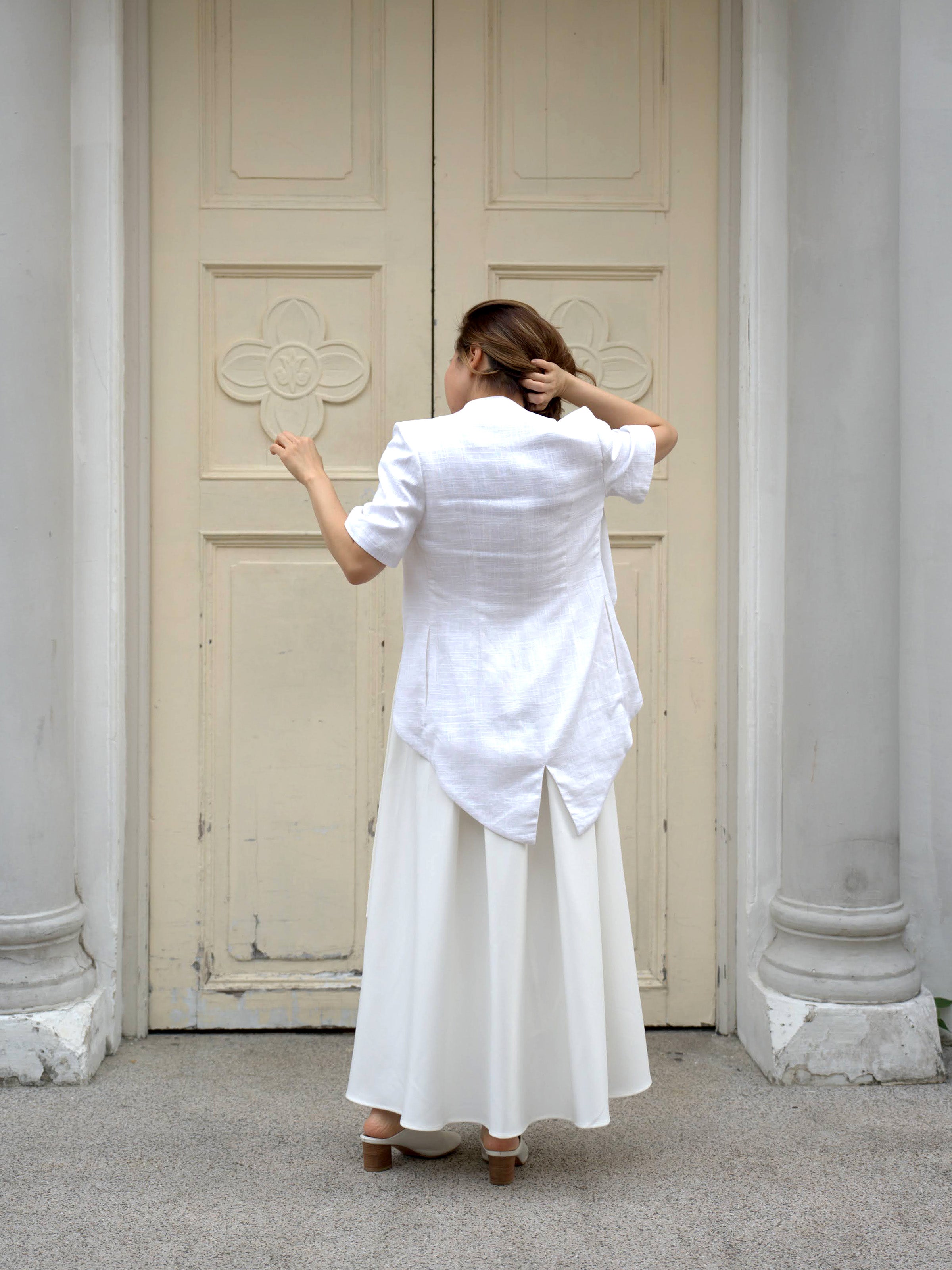 Woman wearing a white outerwear jacket with tailcoat and white skirt by Singapore fashion brand Hadasity.
