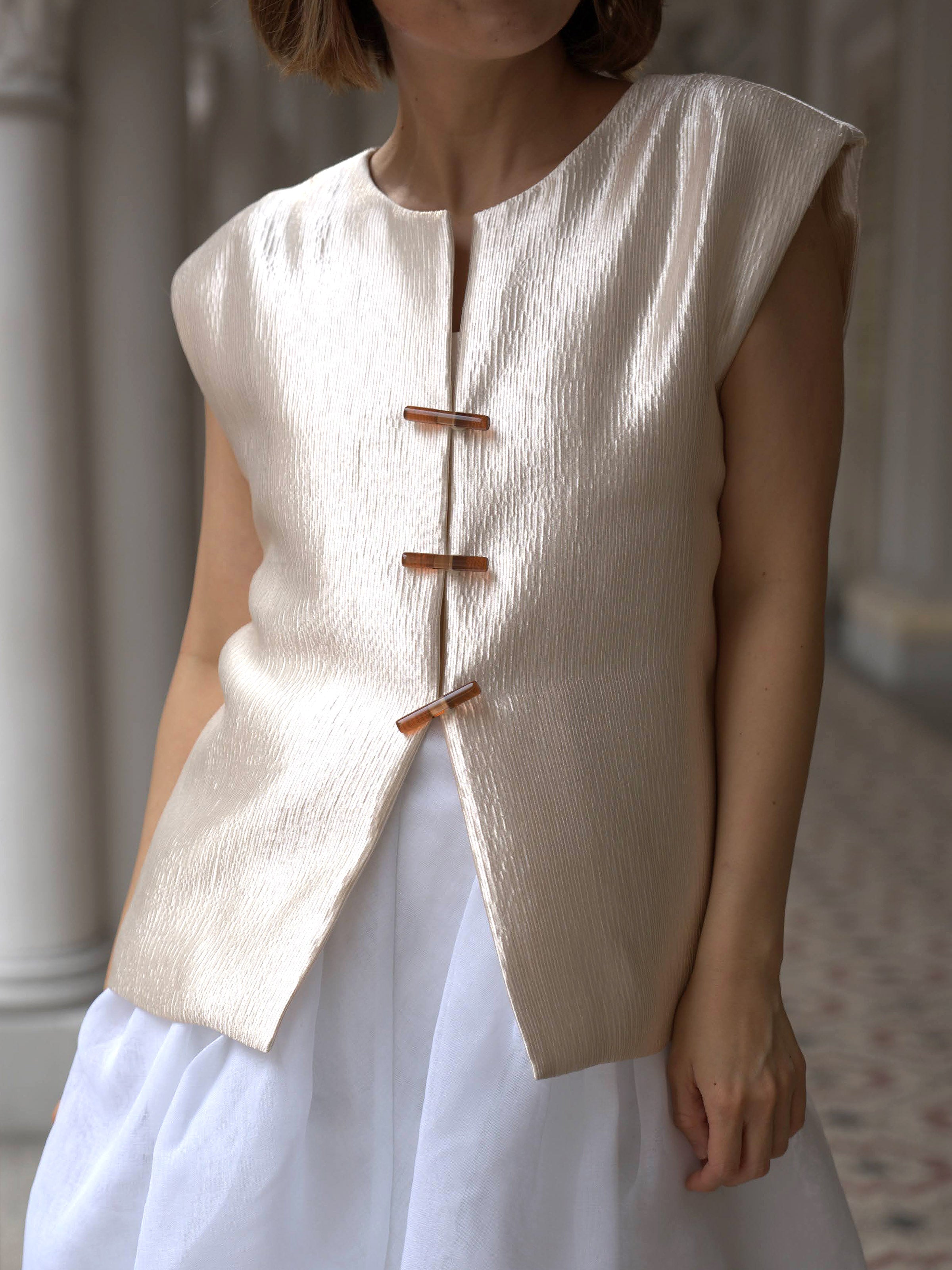 Woman wearing a gold shimmer outerwear vest and white skirt by Singapore fashion brand Hadasity