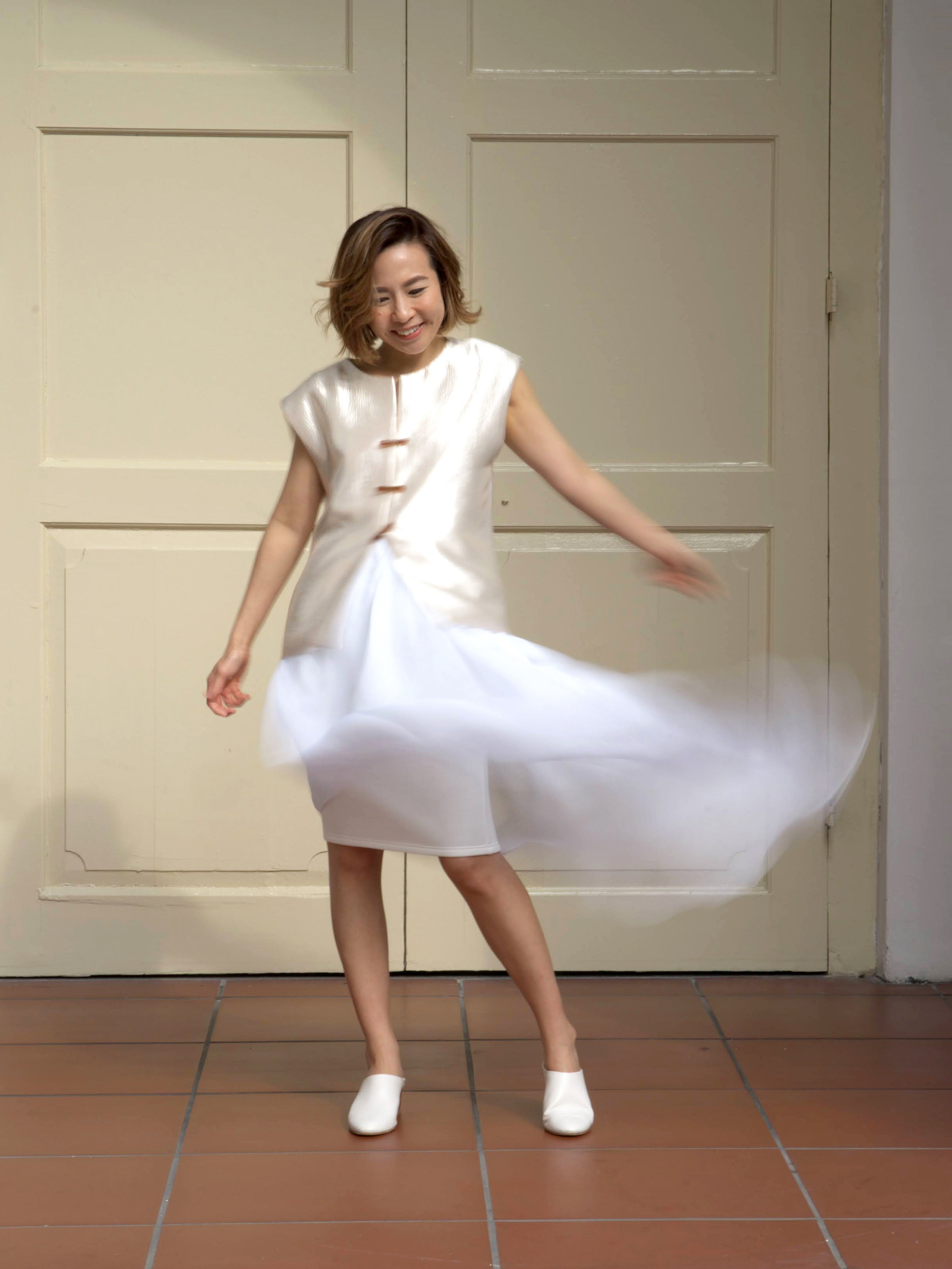 Woman wearing white asymmetrical designer skirt and gold shimmer sleeveless vest by Singapore women's fashion brand Hadasity.