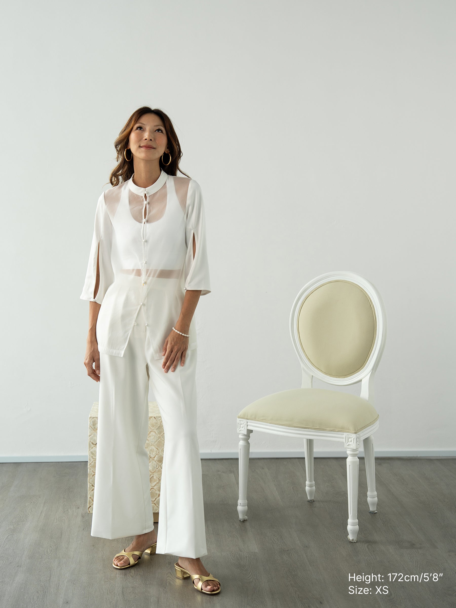 Woman wearing a white sheer jacket and white pants by Singapore fashion brand Hadasity.