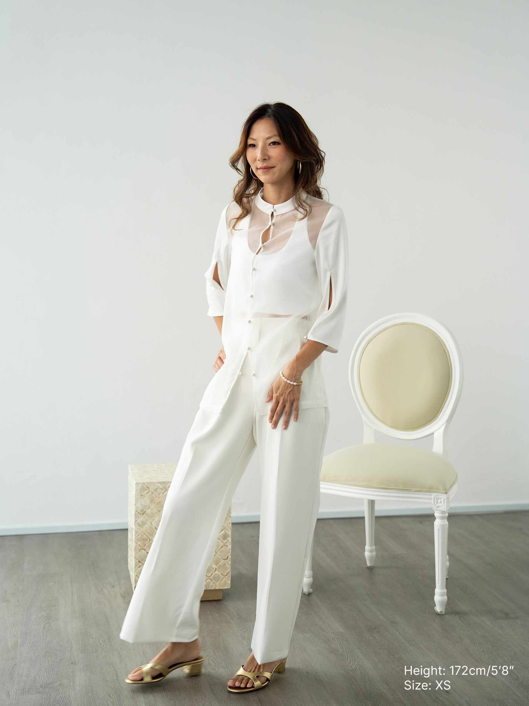 Woman wearing a white sheer jacket and white pants by Singapore fashion brand Hadasity.