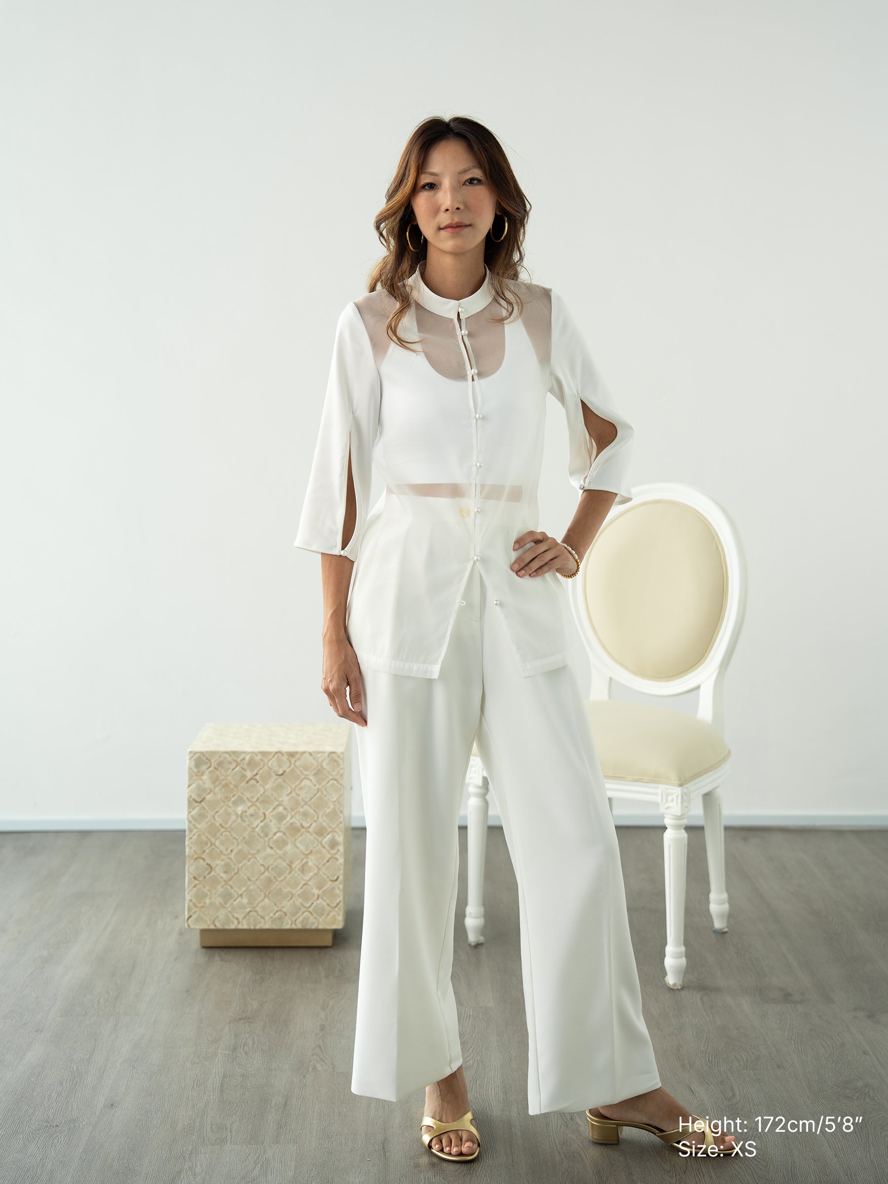 Woman wearing a white sheer jacket and white pants by Singapore fashion brand Hadasity.