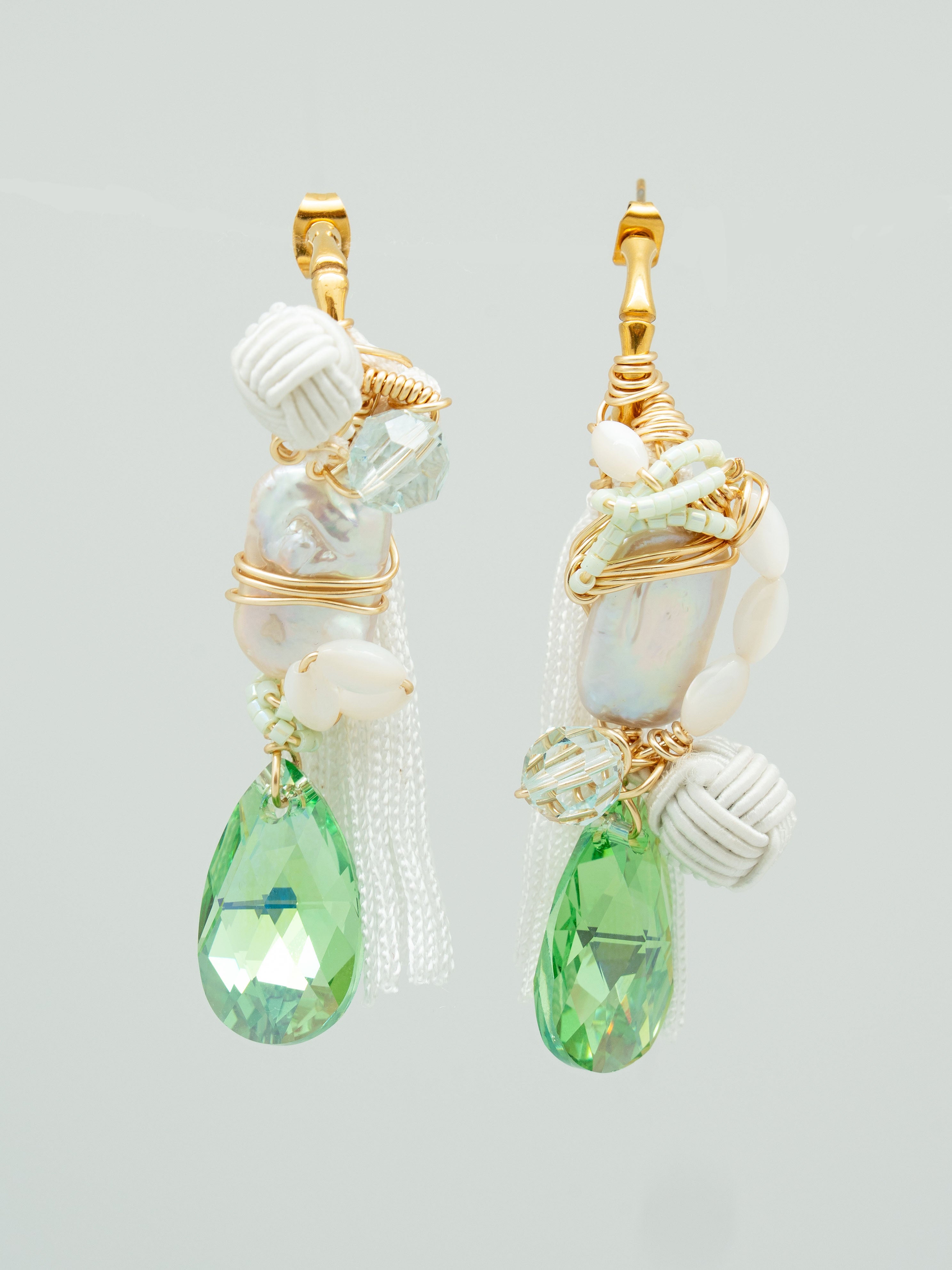 Pair of earrings with green teardrop-shaped swarovski crystals, freshwater pearls, white tassel and fabric elements