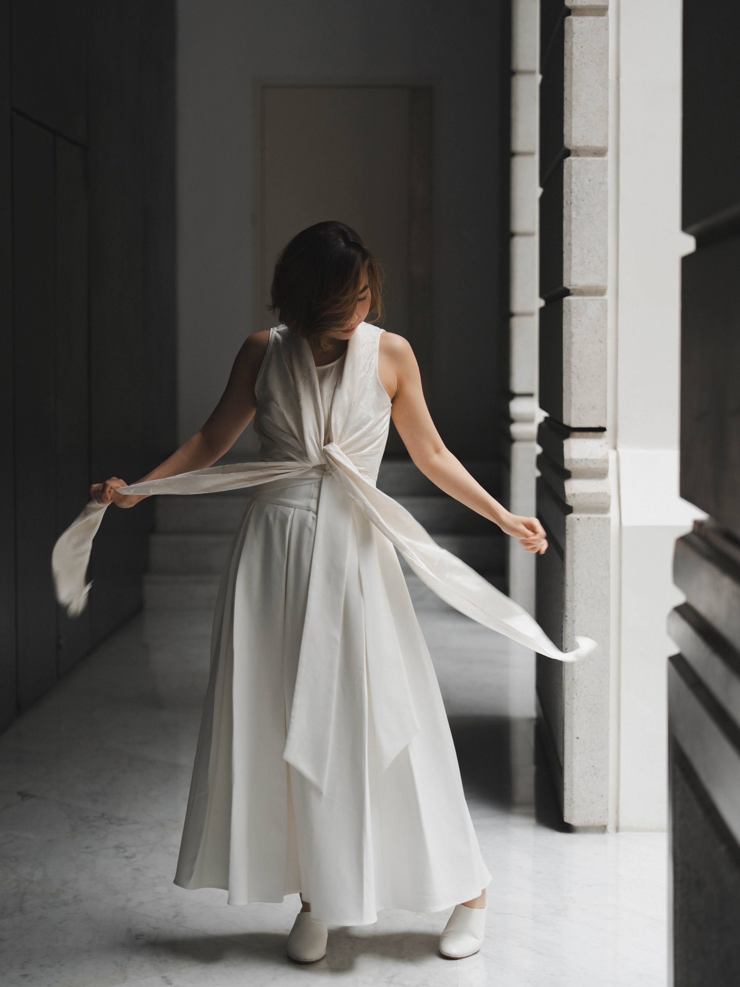 Woman wearing white sleeveless wrapped multi-way top and white skirt by Singapore women's fashion brand Hadasity.