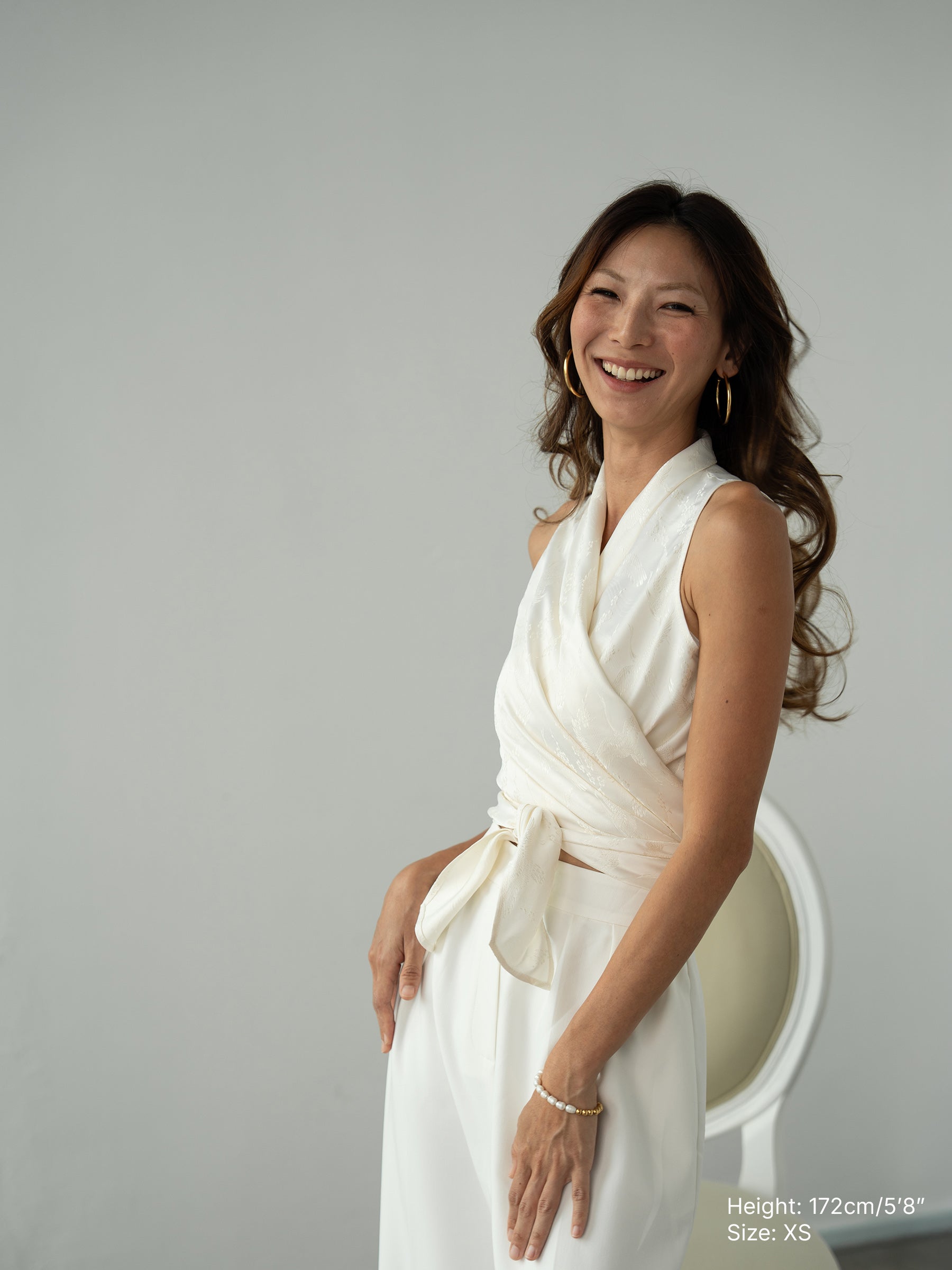 Woman wearing white sleeveless wrapped multi-way top and white pants by Singapore women's fashion brand Hadasity.