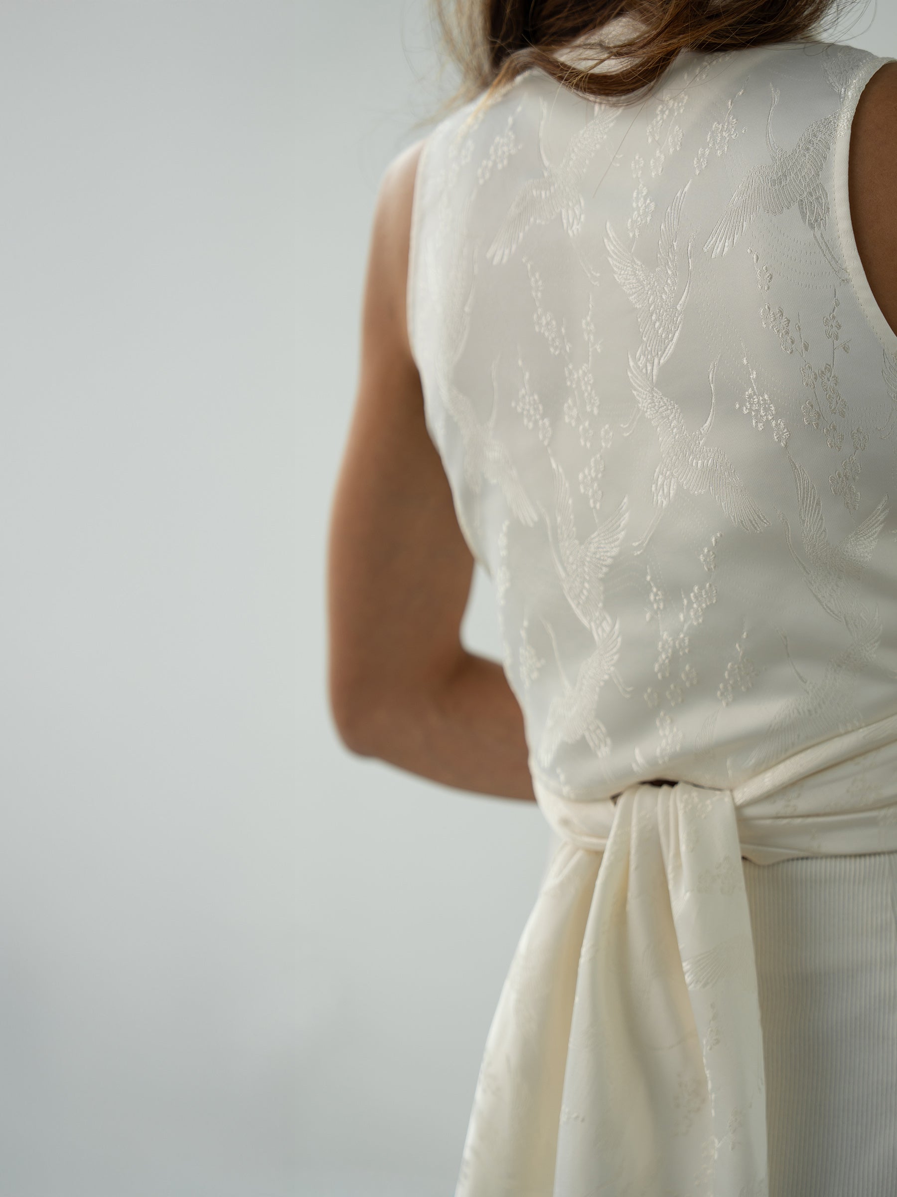 Woman wearing white sleeveless wrapped multi-way top and white pants by Singapore women's fashion brand Hadasity.