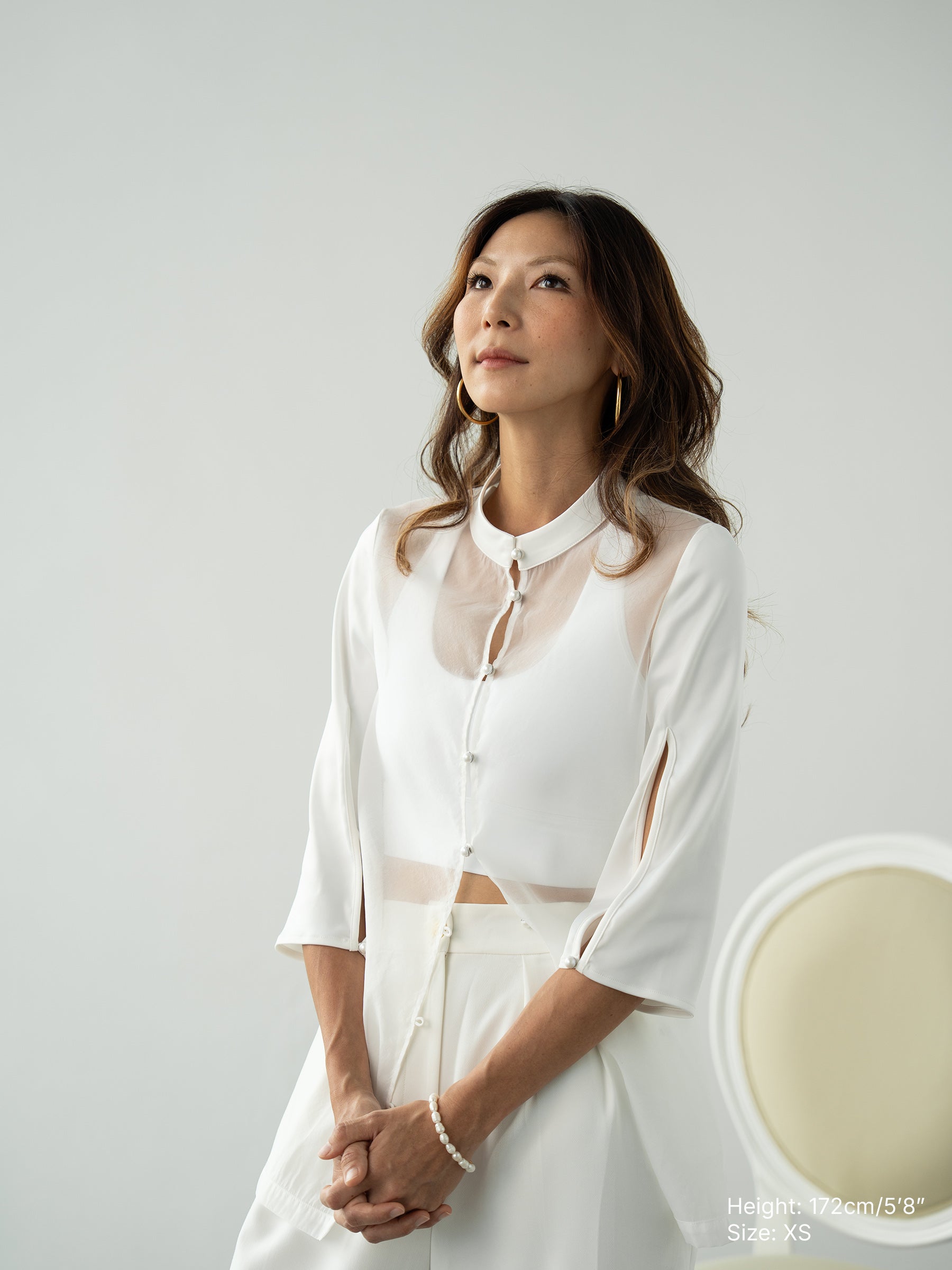 Woman wearing a white sheer jacket and white pants by Singapore fashion brand Hadasity.