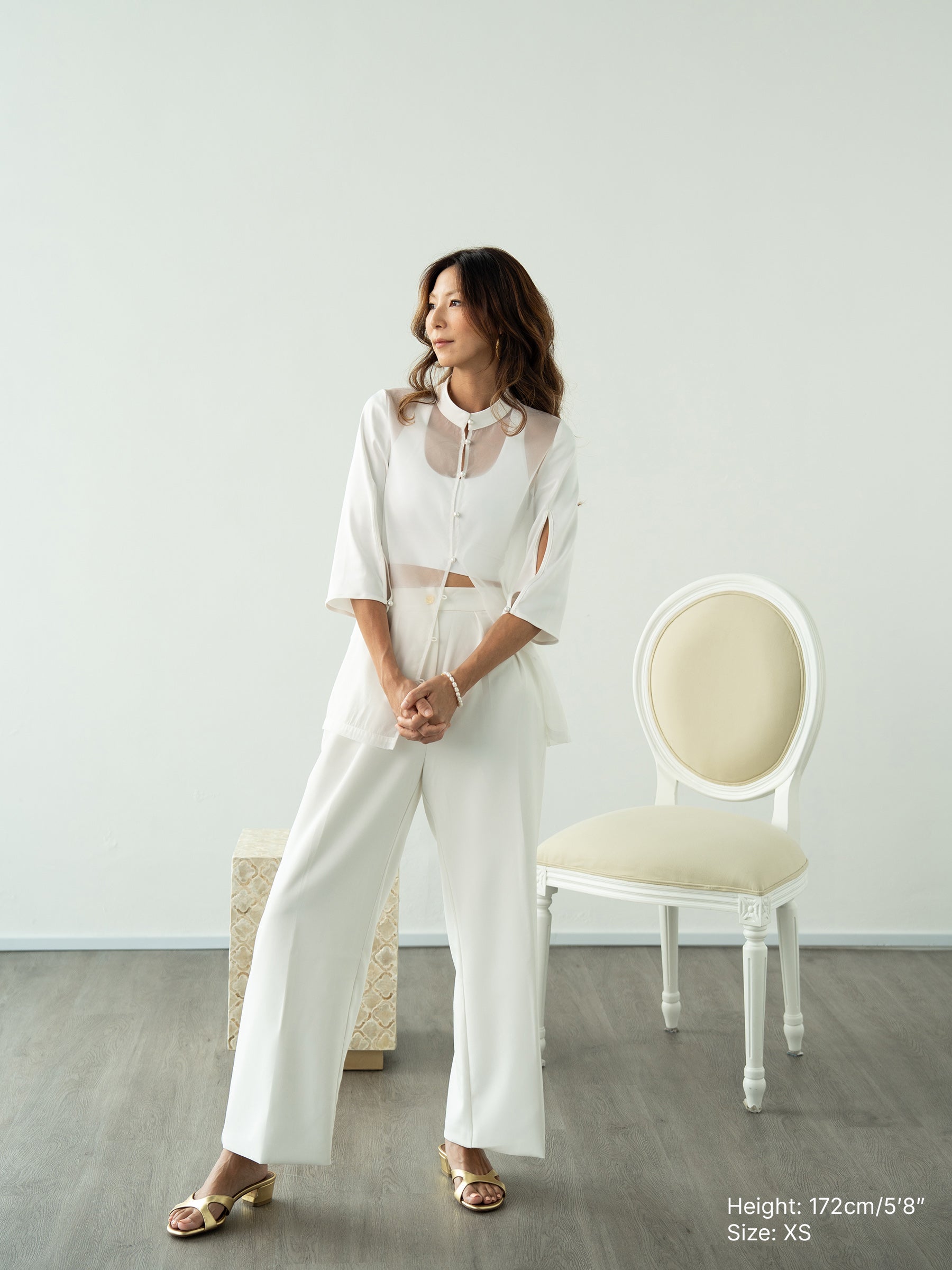 Woman wearing a white sheer jacket and white pants by Singapore fashion brand Hadasity.