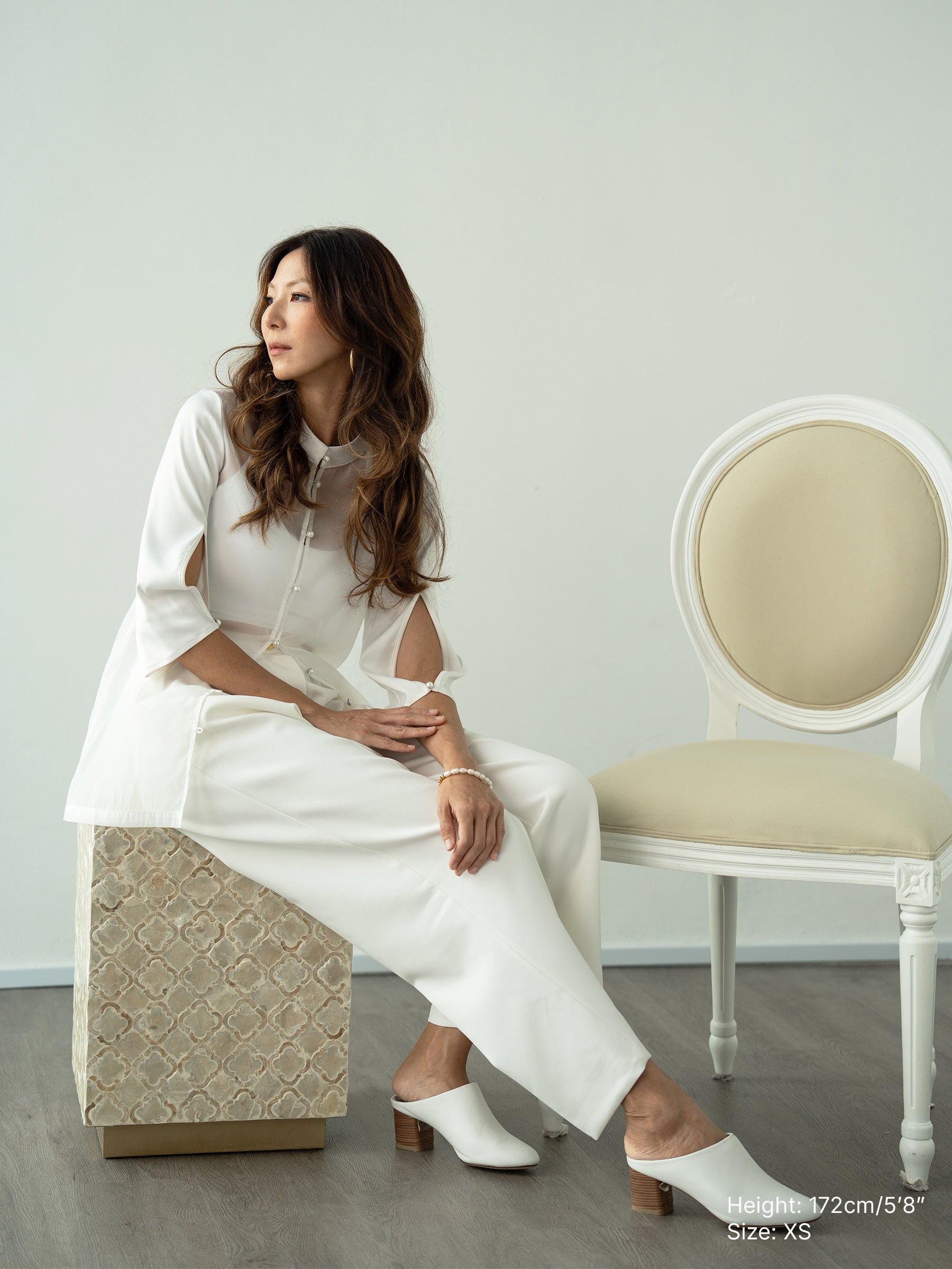 Woman wearing a white sheer jacket and white pants by Singapore fashion brand Hadasity.